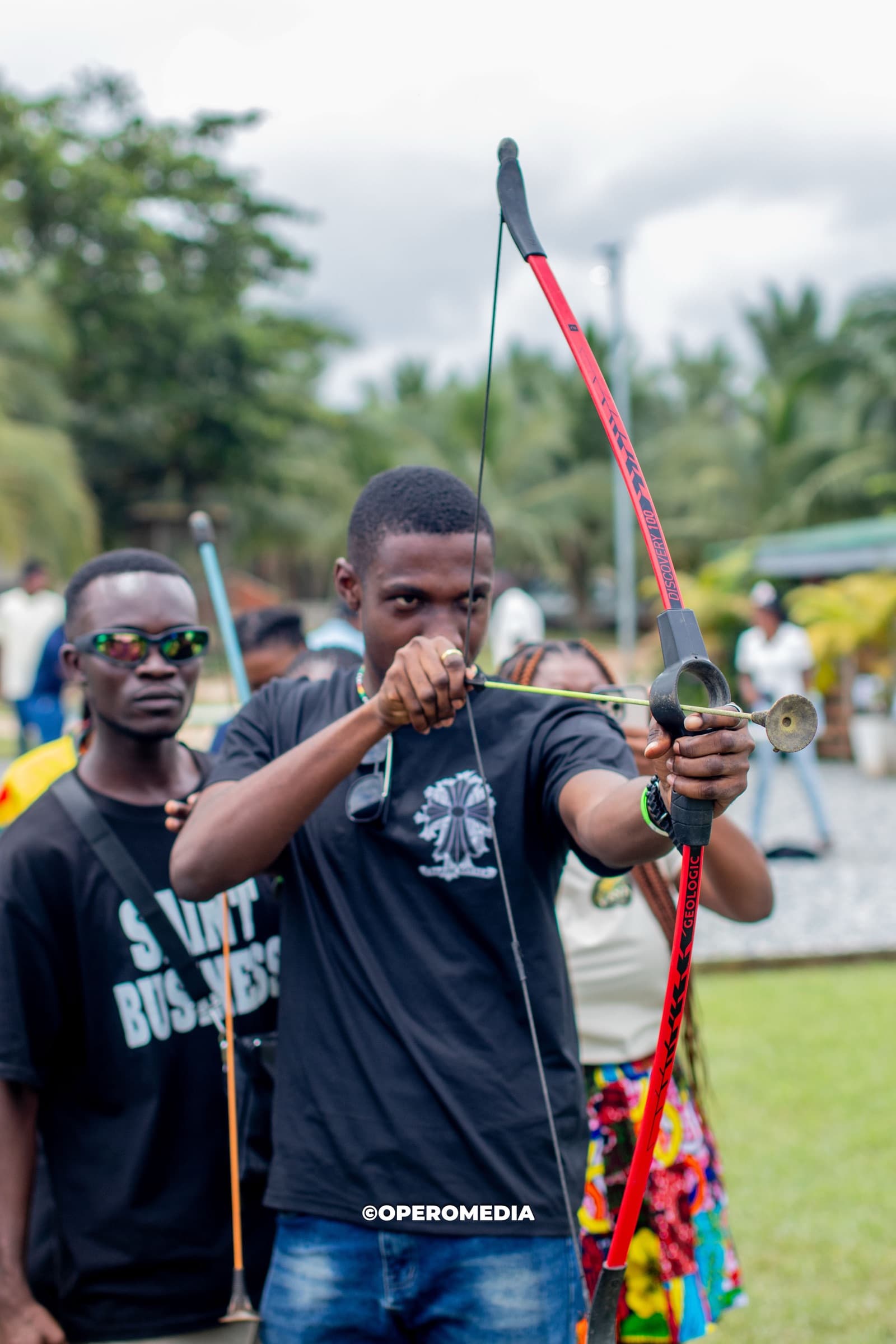 A guest drawing back a bow during archery
